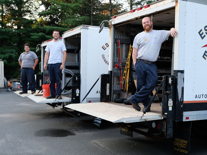 Licensed Esposito's electricians smiling and standing on back ramps of trucks NJ